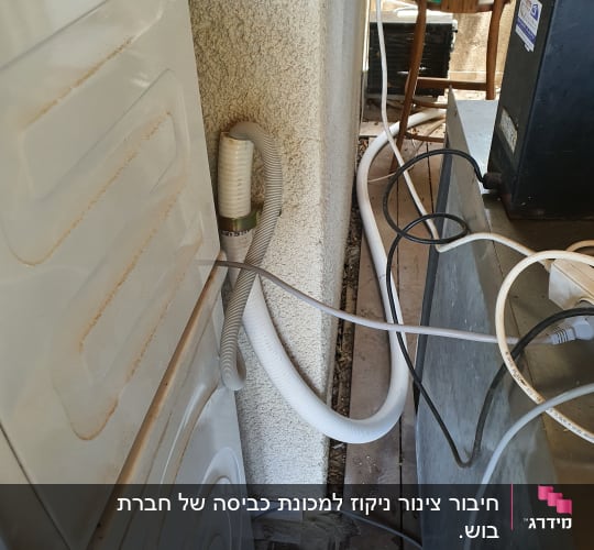 צינור פלסטיק מחובר למכונת כביסה ליד קיר